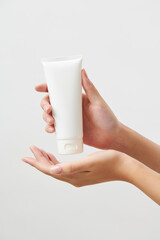 흰색 목각 모형 튜브형 화장품을 들고 있는 여성 모델의 아름다운 손