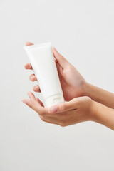 두손으로 흰색 목각 화장품 용기를 손에 받친 여성의 손