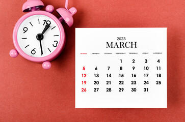 Fototapeta na wymiar The March 2023 Monthly calendar year for 2023 year with alarm clock on red background.