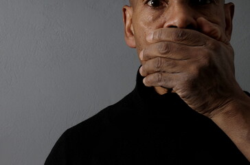 man with hand over mouth gesture keeping quiet on black background stock photo 