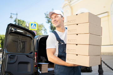 A courier delivering boxes by car to the customer's order address. Dressed in a uniform for...