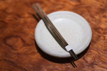 Empty clay plate with a new set of wooden chopstick on a wooden table