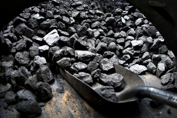 An old shovel and piles of coal in a vintage steam train or locomotive.