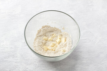 Glass bowl with semolina, flour and butter on a light gray background. Cooking delicious homemade cakes