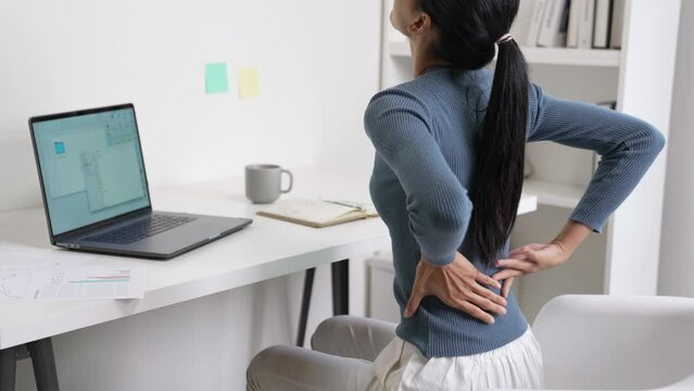 Young Asian business woman suffering from back pain while working. Office syndrome concept.