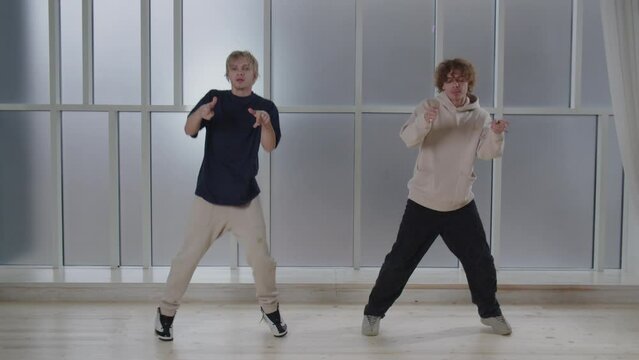 Energetic boys performing contemporary dance together. Studio footage of twin brothers dancing in hip hop style