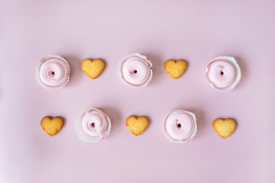 in the center on a pink background are heart-shaped cookies and pink marshmallows in order