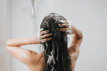 Woman washing hair with shampoo and shower in bathroom, Asian female body and hair care with foam...