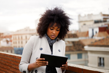 Afro American business woman using a tablet on the roof of a building. Entrepreneur using a tablet