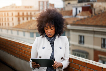 Afro American business woman using a tablet on the roof of a building. Entrepreneur using a tablet