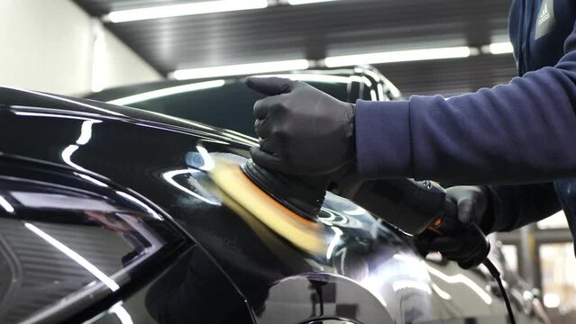 Professional detailing a car in car studio, hands with orbital polisher, scratching remover, vehicle care concept