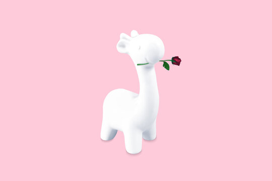 The figure of a giraffe with a rose in its mouth. Pastel pink background.