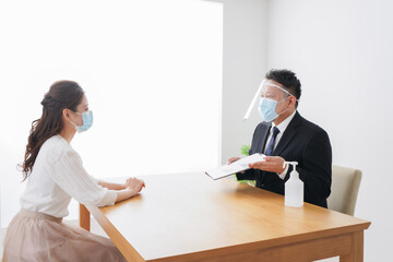 Obraz premium フェイスシールドとマスクをして商談をするビジネスパーソン