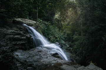 Obraz premium Blurred waterfall stream falls down steep mountain and disappears into deep gorge, Samui, Thailand