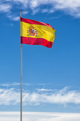 Spanish flag hoisted on the mast in the wind with blue sky - 568060525