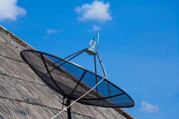 Satellite dish on the roof with blue sky.