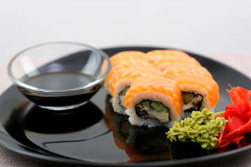 Philadelphia sushi Black plate, black chopsticks, soy sauce, white background, close-up of sushi on black background