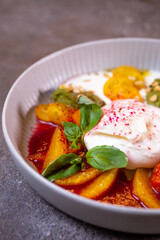 Salad with buratta cheese and tomatoes with pesto sauce in a bowl close-up