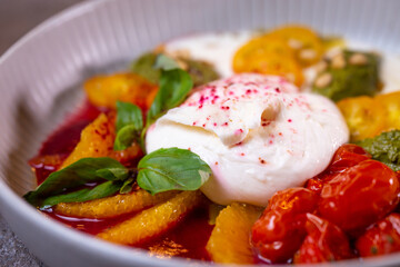 Salad with buratta cheese and tomatoes with pesto sauce in a bowl close-up