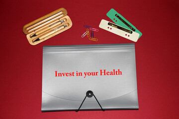 Arbeitsmappe mit dem Titel "Invest in your Health" auf rotem Hintergrund