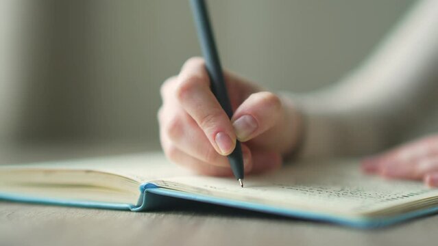 close-up of a female hands taking notes in a notebook notepad using pen on modern desk at home young woman writes in a diary with a pen while sitting at the table Close up commonplace