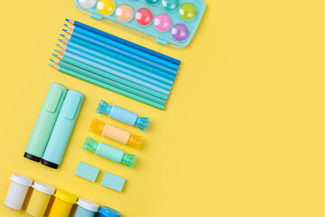 Various colorful material for creativity and art activity is arranged neatly on yellow background.  Stationery and supplies for drawing and craft. Workplace organization.