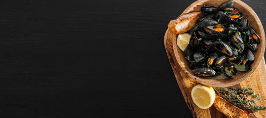 Fresh mussels in a wooden plate with herbs and lemon