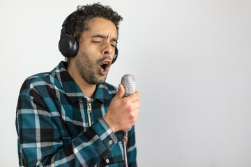 Mixed race man dressed in checked shirt singing into a condenser microphone