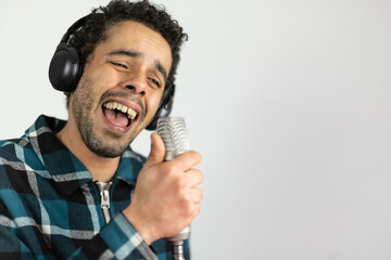 Mixed race man dressed in checked shirt singing into a condenser microphone