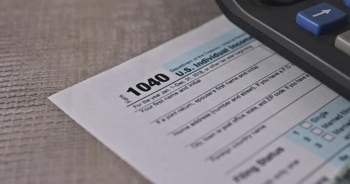 This desk contains 1040 individual tax income form from United States, pen calculator and some US tax return stimulus check