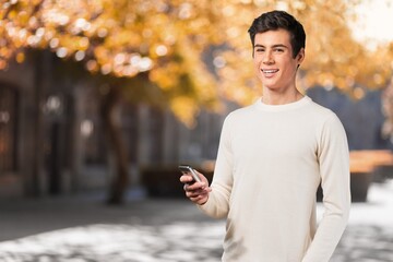 Smiling young person, using smartphone on outdoors.