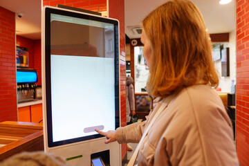 woman makes an order of dishes in the cafe on the self-service terminal. the concept of an...