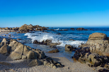 Fototapeta na wymiar Beach with rock formations and crashing ocean wave at Monterey Bay