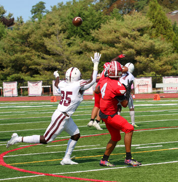 Football Wide Receiver And Defensive Back Looking At The Ball In The Air Trying To Make A Play