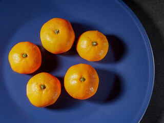 one orange mandarin on blue plate