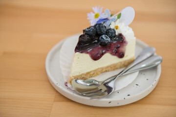 Cheesecake with fresh blueberries on dish and wooden table