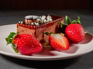 Three chocolates cake with chocolate drips on a black background. Layered cake with milk, black and white chocolate souffle decorated with strawberries on top. Confectionery background with copy space