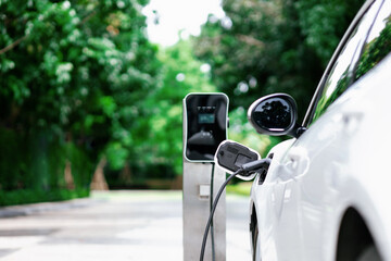Focus closeup electric vehicle plugged in with EV charger device from blurred background of public...