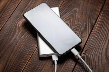 white power bank and smartphone on wooden background.