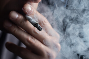 Man smoking a cigarette on black background. close up