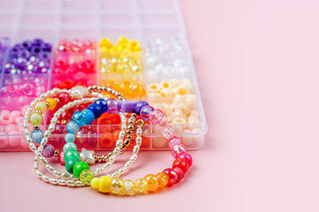 Kids handmade beaded jewelry and different multi-colored beads for children's needlework and crafts in boxes. DIY art activity for kids. Motor skills, creativity and  hobby.