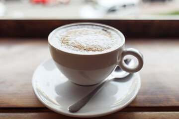 Cappuccino coffee in white cup on the table with the spoon, coffee break concept High quality photo