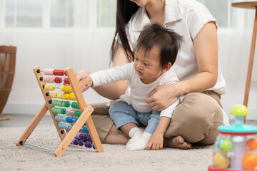 Asian mom teaching baby boy learning and playing toys for development skill at home or nursery...
