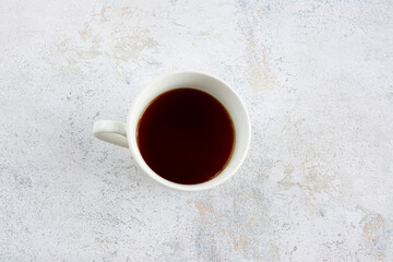 white cup of coffee isolated on concrete background, topview