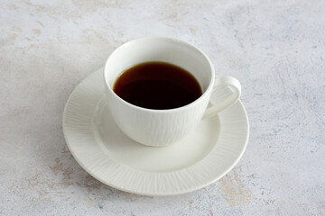 white cup of coffee on white saucer isolated on pastel background, close-up 