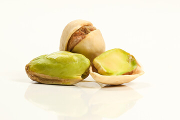 Close up of three roasted salted pistachio nut in shell on white
