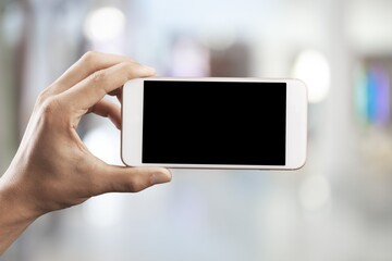 Hand holding mobile phone with a black screen.