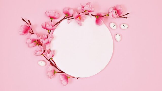 Copy space circle with spring flower decoration on pastel pink background. Stop motion. Flat lay