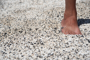Detalle del pie de un hombre bronceado en los rodolitos en forma de palomitas de maíz en blanco y negro en la playa El Hierro o Playa de las Palomitas en Fuerteventura en las Islas Canarias
