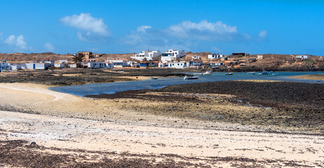 Vista panorámica del pueblo Majanicho lleno de casas coloridas y barcos de pesca en la turística Fuerteventura desde la playa El Hierro o Playa de las Palomitas en la costa de las Islas Canarias